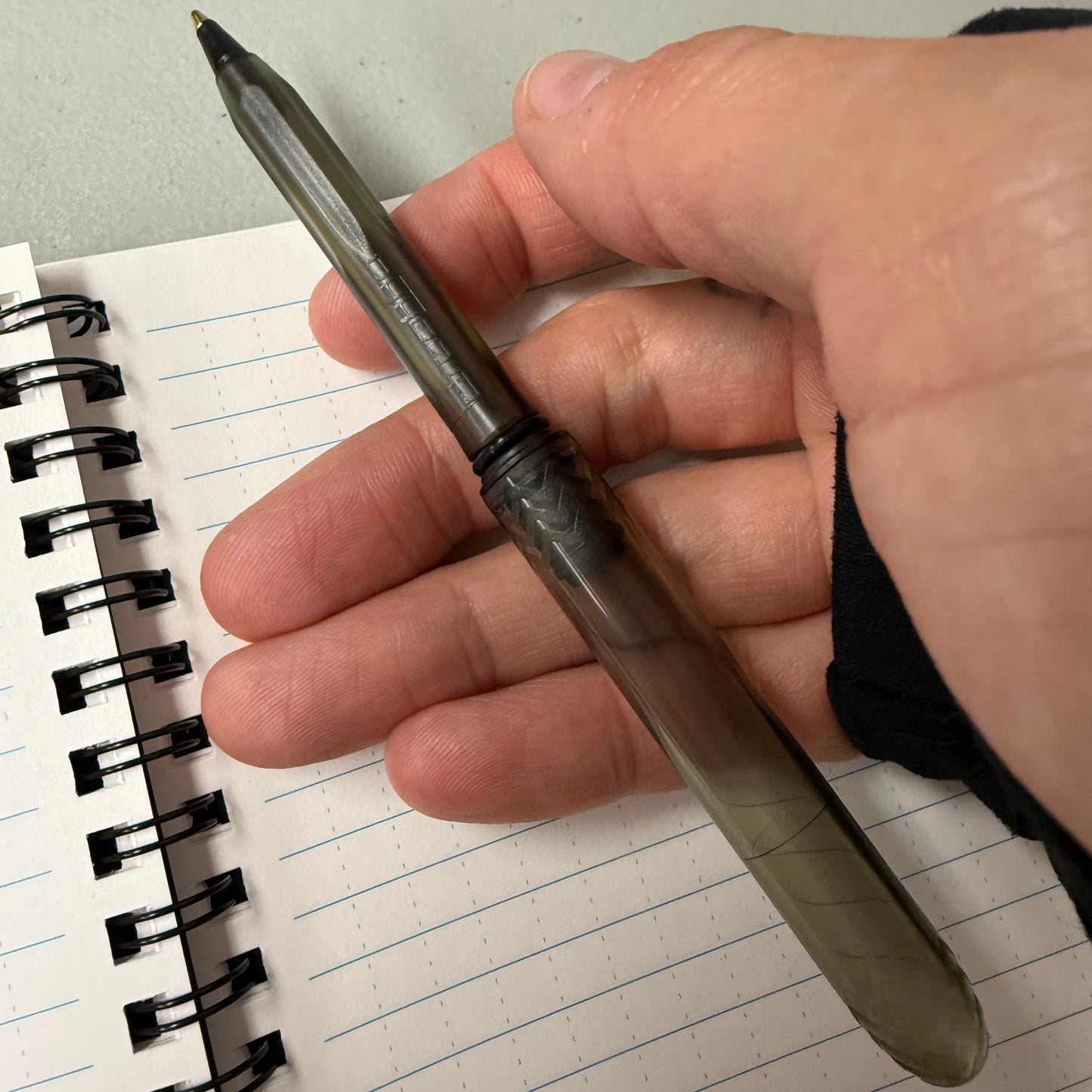 Hand holding a pen over a notebook with lined paper