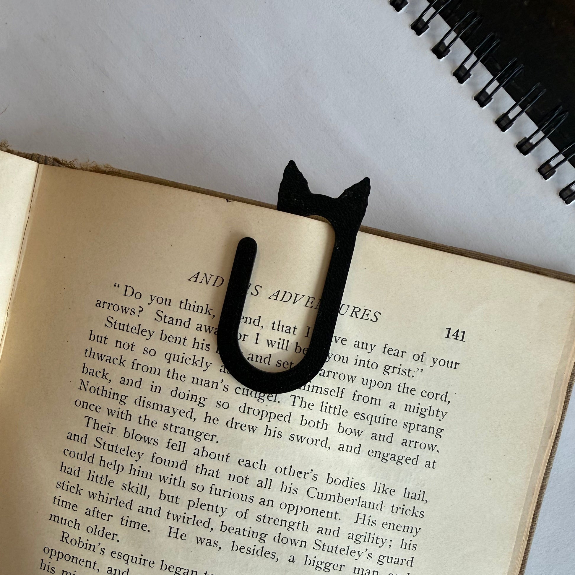Black cat-shaped book marker on an open book