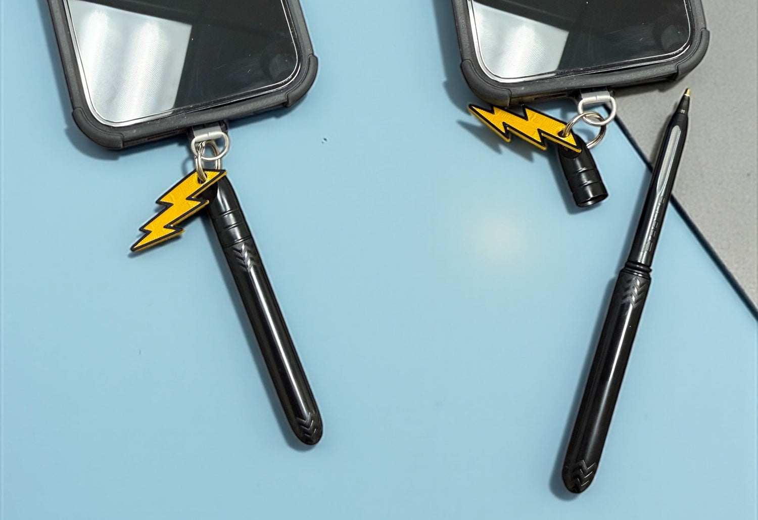 Two black pens with yellow lightning bolt designs on a blue surface
