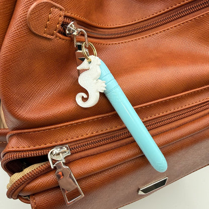 Brown leather bag with a blue pen and white charm on a light background