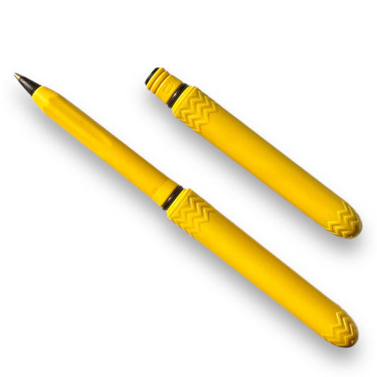 A bright yellow ballpoint pen with a patterned section near the tip.